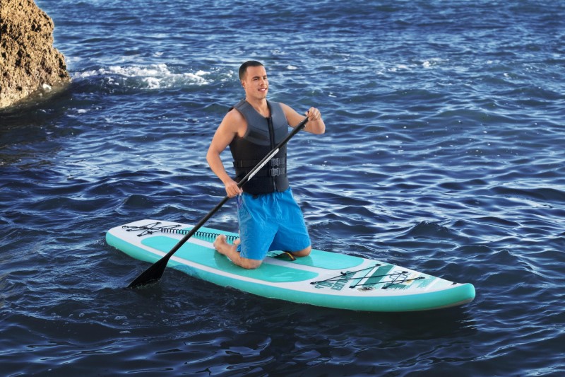 Man zittend op Hydro Force Aqua Glider 10'6 SUP Board op zee