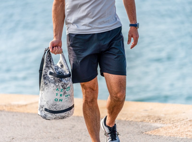 Man draagt Aztron Dry Bag 15 liter op het strand