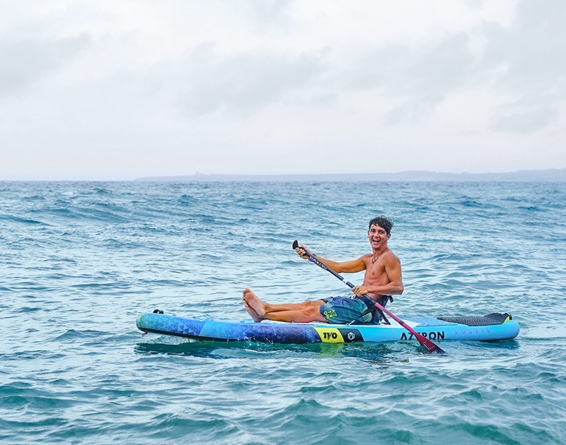 Man zittend op Aztron Soleil 11' Wind SUP Board op zee